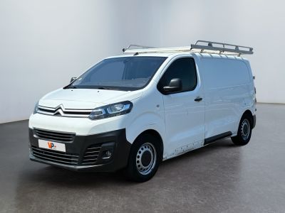 La camionnette blanche est garée dans une pièce aux murs blancs.