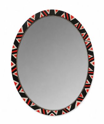 un miroir rond orné de motifs noirs, rouges et blancs