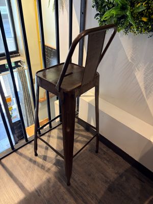 a metal bar stool sitting in front of a window