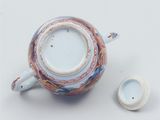 a tea pot and a cup on a white surface