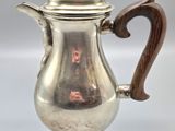 an antique silver coffee pot with a wooden handle on a white background