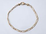 gros plan d'un bracelet en chaîne en or sur fond blanc