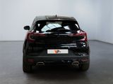 the rear end of a black car parked in a white room