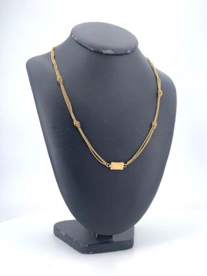 a black mannequin with a gold necklace on it