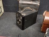 a black camera and a brown case sitting on a table