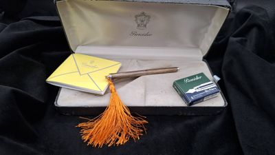 une valise ouverte ornée d'un pompon jaune et d'un bloc-notes