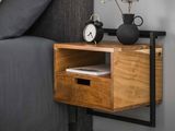 une petite table en bois sur laquelle se trouve une horloge, à côté d'un lit