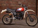 a red and white dirt bike parked in front of a brick wall