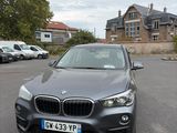 the bmw x1 is parked in a parking lot in front of a house