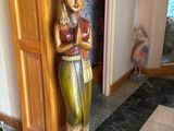 une statue en bois représentant une femme tenant une bouteille de vin