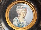 painting of a woman in a blue dress and hat in a gold frame
