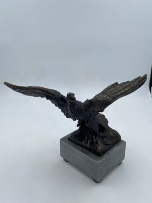 une image représentant une statue en bronze d'un oiseau posée sur un socle en marbre