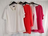 four different colored shirts hanging on a clothes rack in front of a white curtain