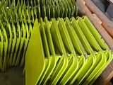 many green chairs stacked on top of each other in a warehouse