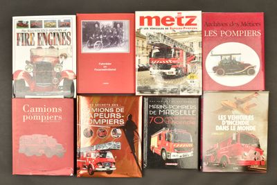 plusieurs livres posés sur une table noire, avec un camion de pompiers rouge en arrière-plan