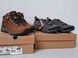 deux paires de chaussures de randonnée posées sur des cartons, sur une table
