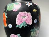 a black vase with colorful flowers on it on a white surface