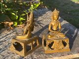 two statues sitting on top of a stone slab