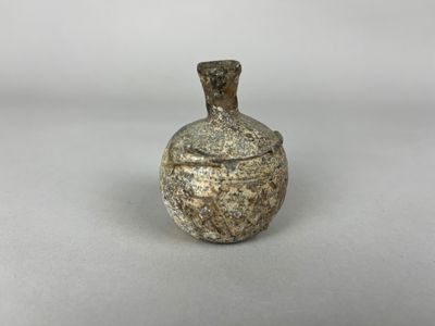 un gros plan d'un petit vase muni d'un couvercle posé sur une table