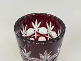 a red glass bowl with white flowers in it