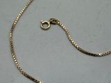 a gold chain with a clasp on a gray surface