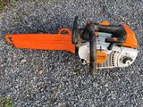 an orange chainsaw sitting on the ground next to some gravel