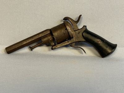 un vieux revolver avec une poignée en bois sur une surface blanche