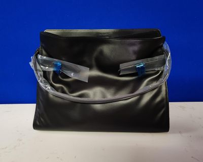 un sac à main noir muni de deux fermetures éclair, posé sur une table
