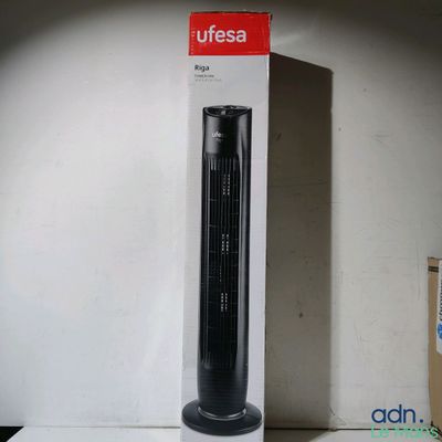 un ventilateur noir posé sur une table blanche, à côté d'une boîte