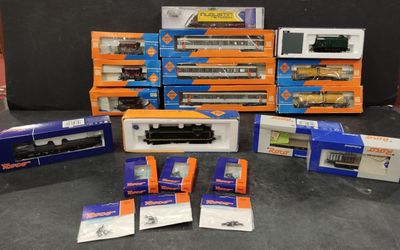 tout un tas de trains miniatures différents, rangés dans des boîtes sur la table