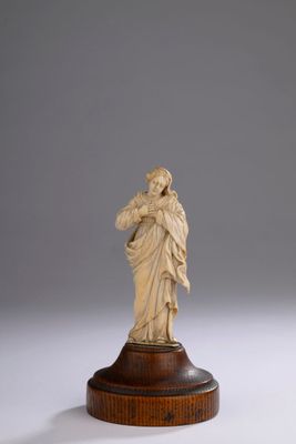 une figurine en ivoire représentant une femme tenant un enfant dans ses bras, posée sur un socle en bois