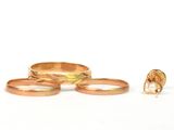 trois bagues en or et une bague ornée d'une perle sur fond blanc