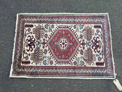 un tapis rouge et blanc posé par terre à côté d'une paire de chaussures