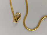 a close up of a gold chain with a clasp on a white surface