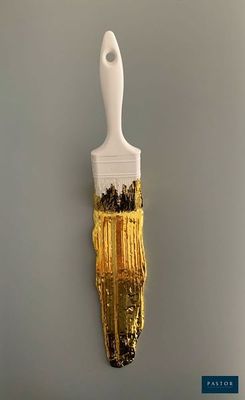 un pinceau blanc avec de la peinture dorée sur un mur gris