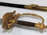 a gold colored sword with a black handle on a white table
