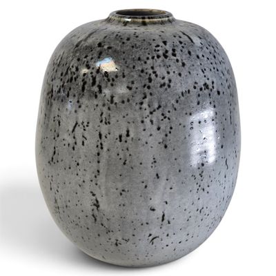 un vase gris posé sur une surface blanche