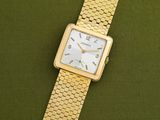 a close up of a gold wrist watch on a green surface