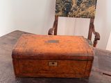 an old wooden box sitting on a table with a chair in the background