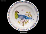 une assiette sur laquelle est peint un oiseau sur fond noir