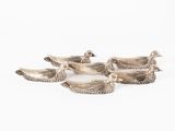 five silver ducks sitting on top of each other on a white surface