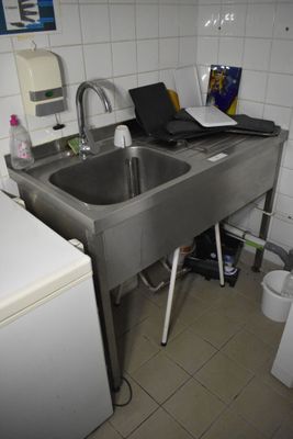 une petite cuisine avec un évier et un ordinateur portable posé sur le plan de travail