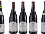 six bottles of wine are lined up on a white surface