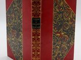 un vieux livre à la couverture rouge et à la bordure dorée