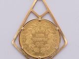 a gold coin in a diamond shaped pendant on a white surface