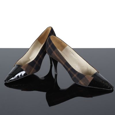 une paire d'escarpins à carreaux noirs et marron posés sur une surface noire