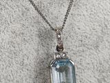 a necklace with a blue topaz stone and diamonds on it