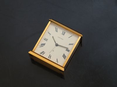 a square clock with roman numerals on a black surface