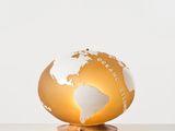 un globe doré et blanc posé sur un socle en bois