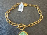a gold bracelet with a green leaf charm on it